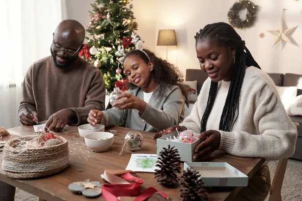 Gelukkig jonge ouders en hun schattige dochter het bereiden van cadeautjes — Stockfoto