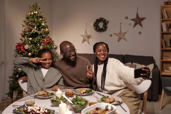 Gelukkig jong gezin van drie maken selfie door feestelijke tafel — Stockfoto