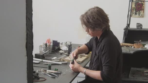 スタジオのワークベンチに座ってリング用のワックス型を作る女性宝石商のPanショット — ストック動画