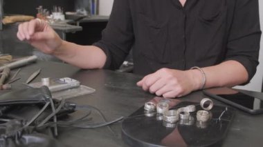 Tanınmayan kadın kuyumcunun orta bölümü. Metal halkayı tartıp keseye koyuyor.