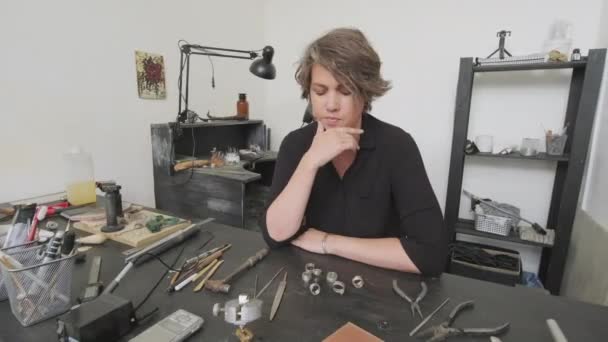 Schwenkporträt Einer Nachdenklichen Juwelierin Die Tisch Atelier Sitzt Metallringe Betrachtet — Stockvideo