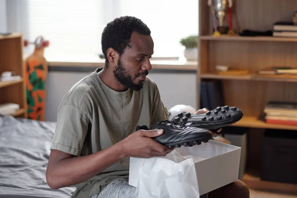 Afrikaanse man houdt paar nieuwe zwarte trendy sportschoenen over open doos — Stockfoto