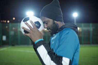 Alnında futbol topu olan genç sporcunun yan görüntüsü