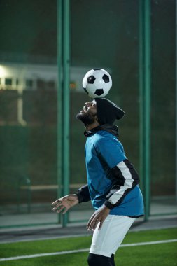 Spor üniformalı genç ve yakışıklı bir adam topla egzersiz yapıyor.