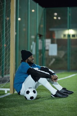 Genç ve dinç futbolcu sıkı çalışmadan sonra ağda oturuyor.