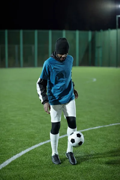 Młody afrykański piłkarz kopie piłkę nożną na boisku — Zdjęcie stockowe