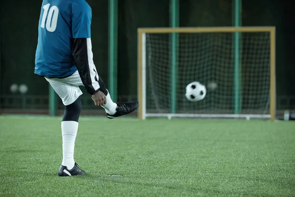 Вид сзади на низкую секцию футболиста, пинающего футбольный мяч — стоковое фото