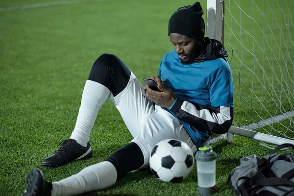 Jonge rustgevende sporter scrollen in smartphone na de training — Stockfoto