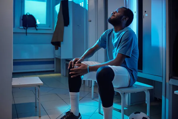 Afrikaanse voetballer in sportuniform raakt knie in pijn — Stockfoto