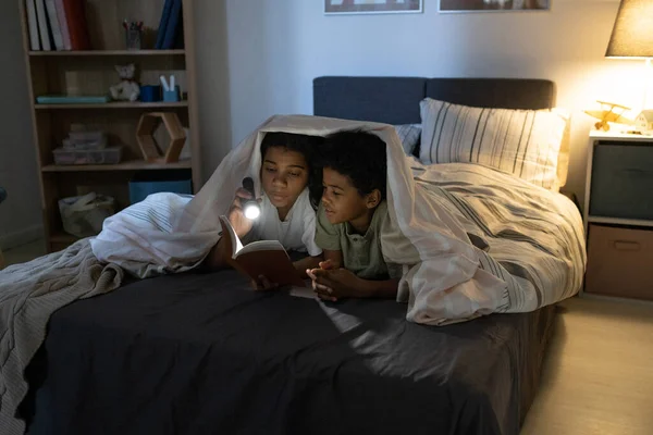 Sister Reading Book To Brother At Night — Stock Photo, Image