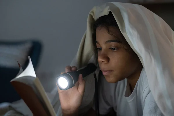 Zwart meisje lezen boek met zaklamp — Stockfoto