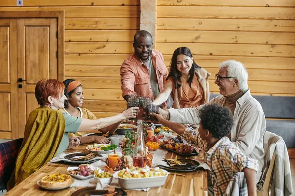 Сучасна міжрасова сім'я смердить з напоями над сервірованим столом — стокове фото