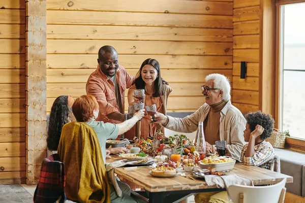 Glad interracial familj på tre generationer skålar vid festligt bord — Stockfoto