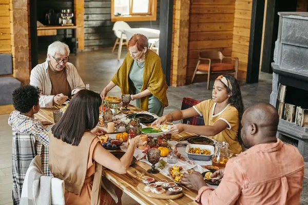 Stor rasblandad familj sittandes vid serverat festbord — Stockfoto
