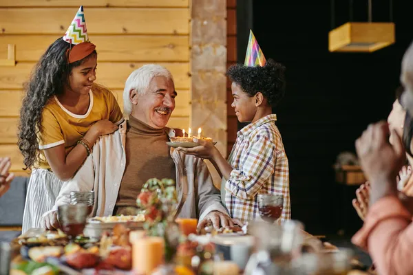 Gelukkig oud man kijken naar zijn interraciale kleinzoon met verjaardag taart — Stockfoto