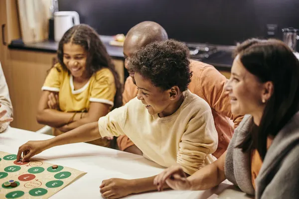 Carino allegro ragazzo mettendo chip sul numero di gioco da tavolo — Foto Stock