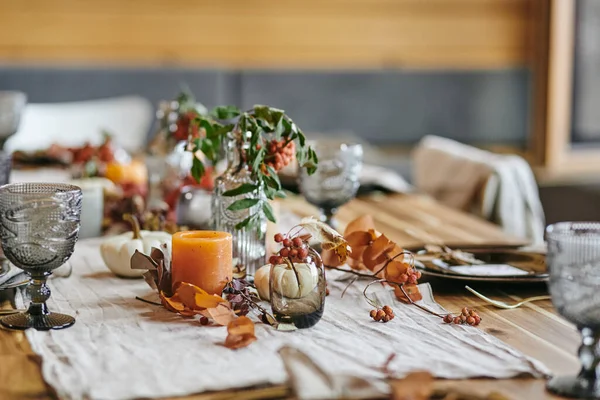 Still life of autumn leaves in vase and bottle on served festive table — Stock Photo, Image