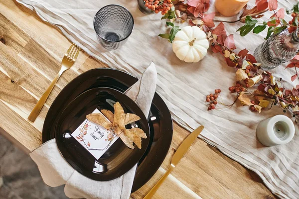 Flatlay of plates with invitation for family dinner and dry autumn leaves — Stock Photo, Image