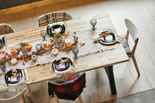 Parte del lungo tavolo da pranzo in legno servito con stoviglie e decorazioni — Foto Stock