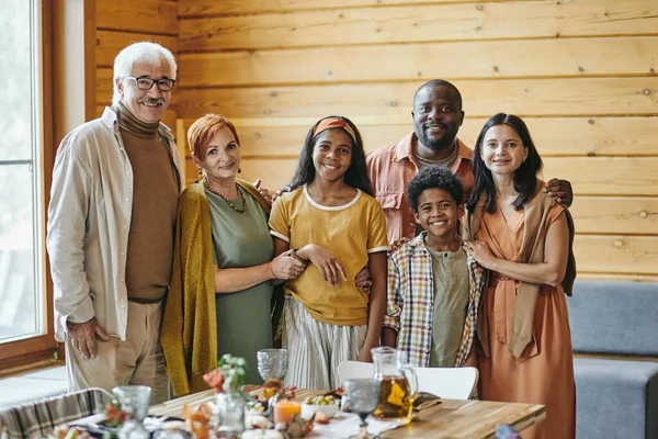 Щаслива міжрасова сім'я з шести стоячих за святковим столом — стокове фото