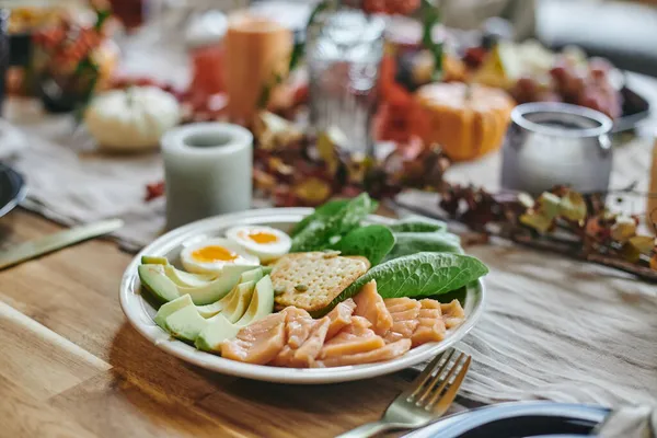 Prato com abacate fresco fatiado, folhas de espinafre, ovo cozido pela metade, biscoito e peixe picado — Fotografia de Stock