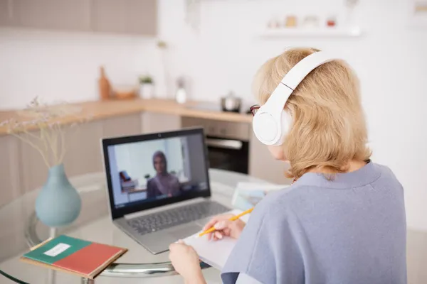 Vue arrière d'une étudiante mature prenant des notes devant un ordinateur portable — Photo