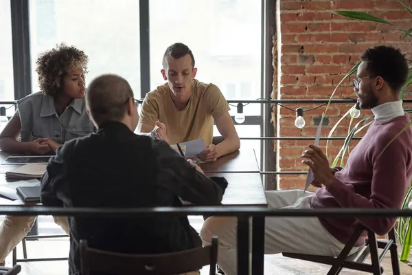 Cuatro gerentes reunidos por mesa para la discusión de documentos financieros —  Fotos de Stock