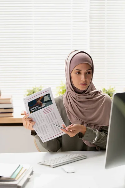 Jonge moslim vrouwelijke leraar in hijab wijzend op financieel document — Stockfoto