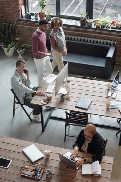 Dois jovens colegas passando por seus colegas de trabalho enquanto se deslocam ao longo do escritório — Fotografia de Stock