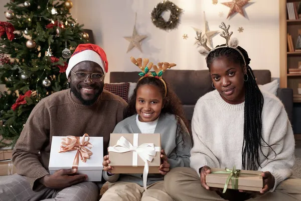 Família africana feliz de três prendendo presentes de Natal — Fotografia de Stock