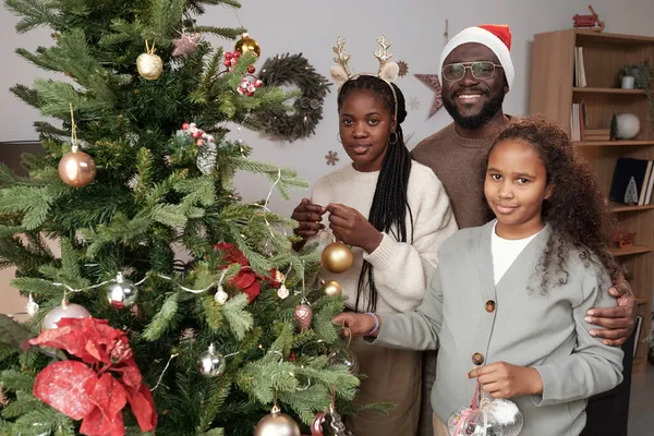 Jovem feliz em Santa cap abraçando sua esposa e sua filha bonito — Fotografia de Stock