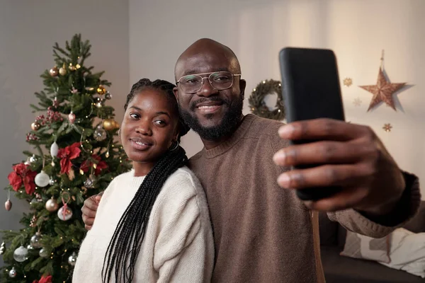 Feliz joven pareja africana mirando a la cámara del teléfono inteligente mientras hace selfie —  Fotos de Stock