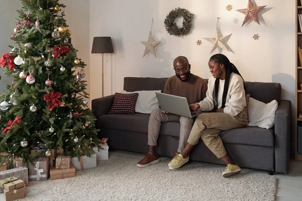 Feliz jovem casal com laptop compras on-line enquanto sentado no sofá — Fotografia de Stock