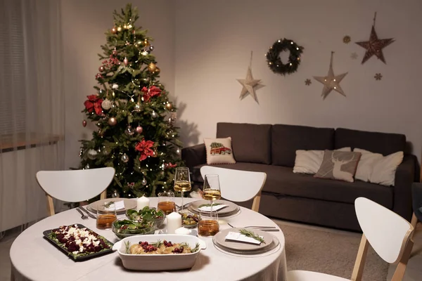 Mesa redonda servida con comida casera contra árbol de Navidad y sofá — Foto de Stock