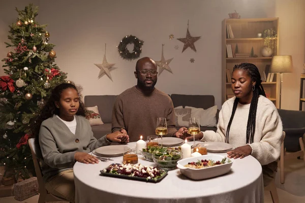 Família cristã contemporânea de três rezando antes do jantar festivo — Fotografia de Stock