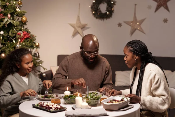 Glad afrikansk familj på tre personer som interagerar vid serverat festbord — Stockfoto