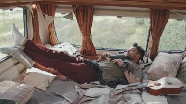 遅い追跡の若い男リラックスしたベッドで居心地の良いキャンパー駐車で森の中で風の強い夏の日 — ストック動画