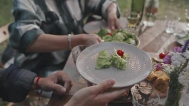 Yavaş yavaş, tanınmayan bir kadının yaz günü dışarıda yemek yerken misafirine salata servisi yapması.