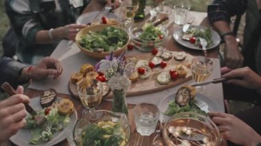 Yüksek açılı, tanınmayan insanların dışarıda masada oturup yaz günü yemeklerin tadını çıkardığı bir çekim.