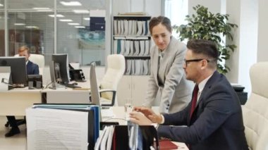 Resmi olarak çalışan kadın ve erkek şirket yöneticilerinin bilgisayar monitörlerine bakıp ofiste işleri tartışırken orta boy görüntüleri.