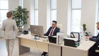 Resmi olarak bayan kişisel asistanın resmi görüntüsü ofiste bilgisayar üzerinde çalışan takım elbiseli bir erkek yöneticiye doğru yürüyor. Ona mali belgeleri gösteriyor ve tartışıyorlar.