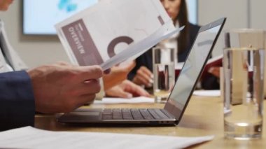 Tanımlanamayan takım elbiseli bir işadamının, toplantı odasında oturmuş dizüstü bilgisayarında daktilo yazarken orta bölümün izini sürüyorum.