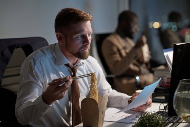 Çin lokantası yiyip bilgisayar ekranına bakmakla meşgul.