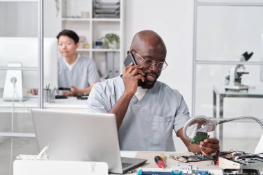 Genç Afrikalı tamirci cep telefonundan müşteriye konuşuyor