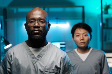 İki genç kültürler arası laboratuvar çalışanı kameraya bakıyor.