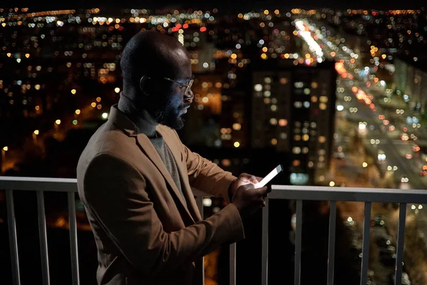Afrikanischer Geschäftsmann in Formalbekleidung schaut sich Kontakte im Handy an — Stockfoto