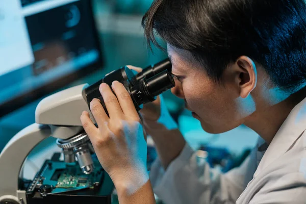 Joven técnico asiático mirando en microscopio — Foto de Stock
