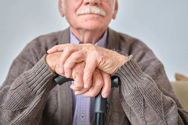 Älterer Mann sitzt mit Krücke — Stockfoto