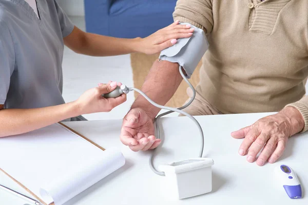 Медсестра вивчає кров'яний тиск пацієнта — стокове фото