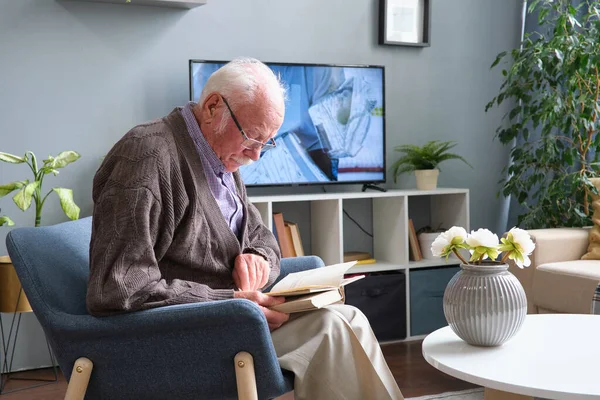 Homem sênior lendo um livro em casa — Fotografia de Stock